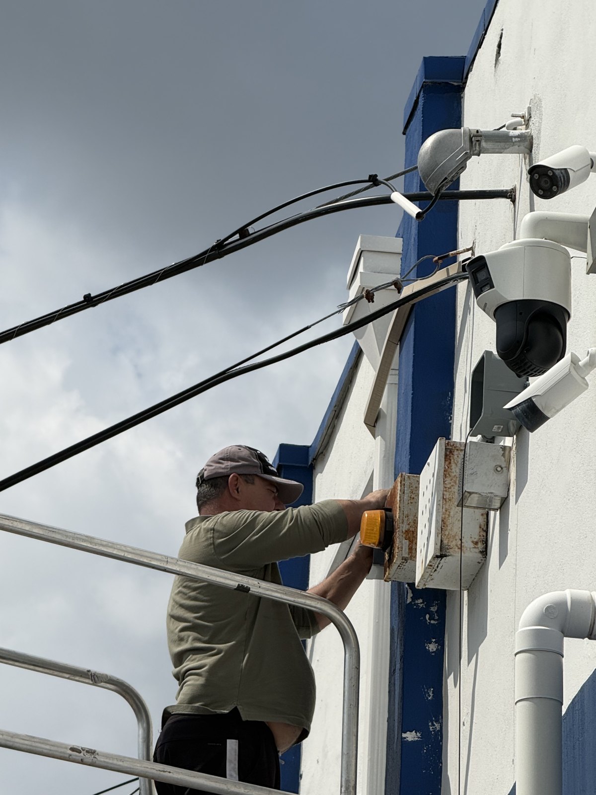 DYBoardsec technician installing exterior IP security cameras and a PTZ dome on a commercial building in South Florida